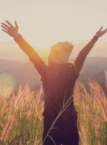 Person with hands in the air standing in a field