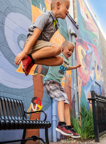 Kids playing on bench in front of wall mural