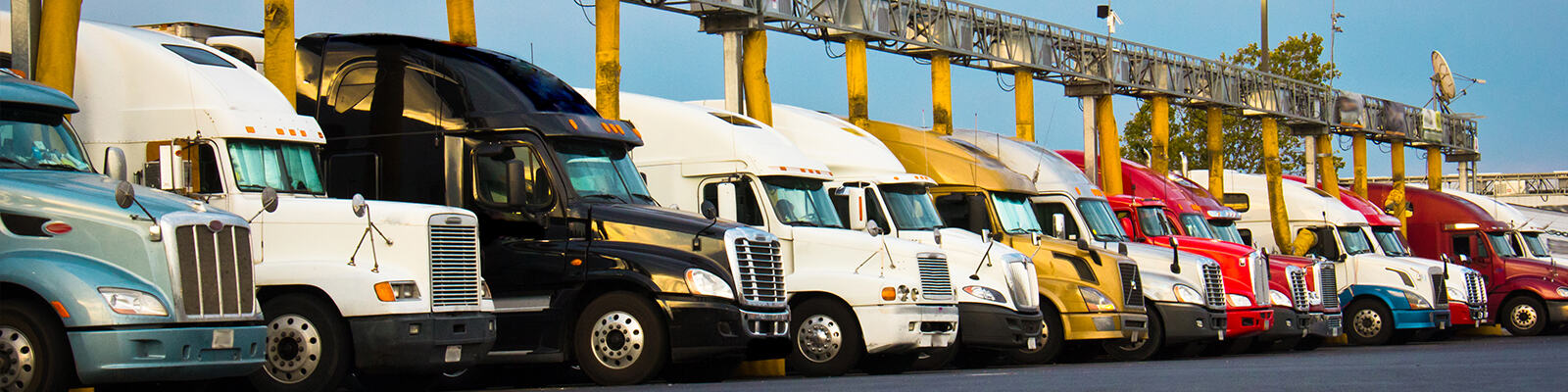 Semi trucks filling with fuel at a truck stop.