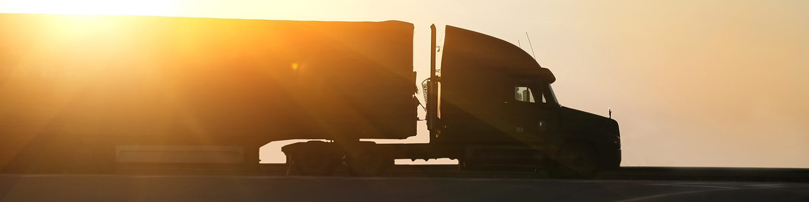 Semi truck driving on the road at sunset