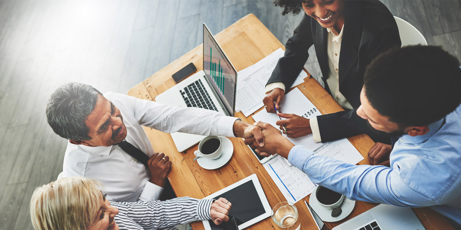 four people in a meeting laughing shaking hands