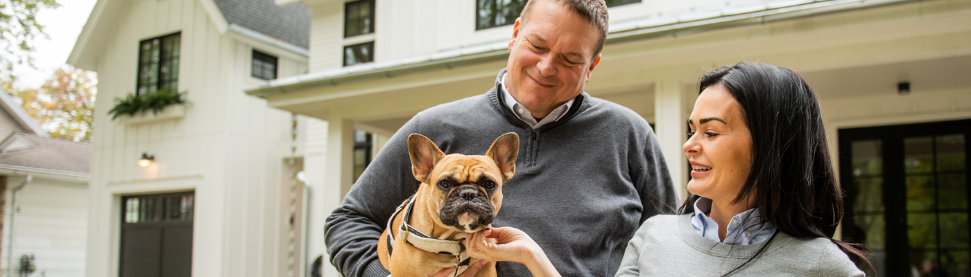 Couple with dog in front of home