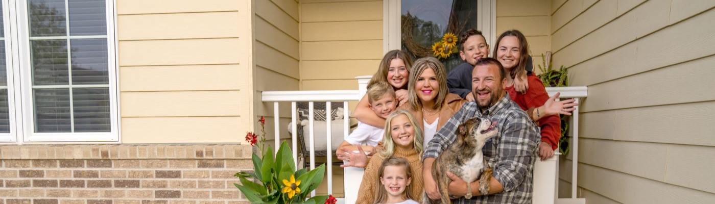 Large family in front of house with dog. 